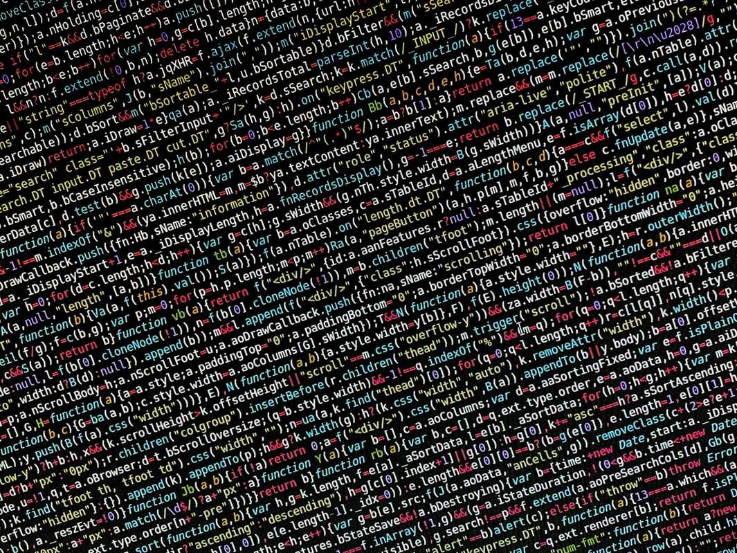 Laptop screen showing programming work at a desk, colorful programming code on a screen