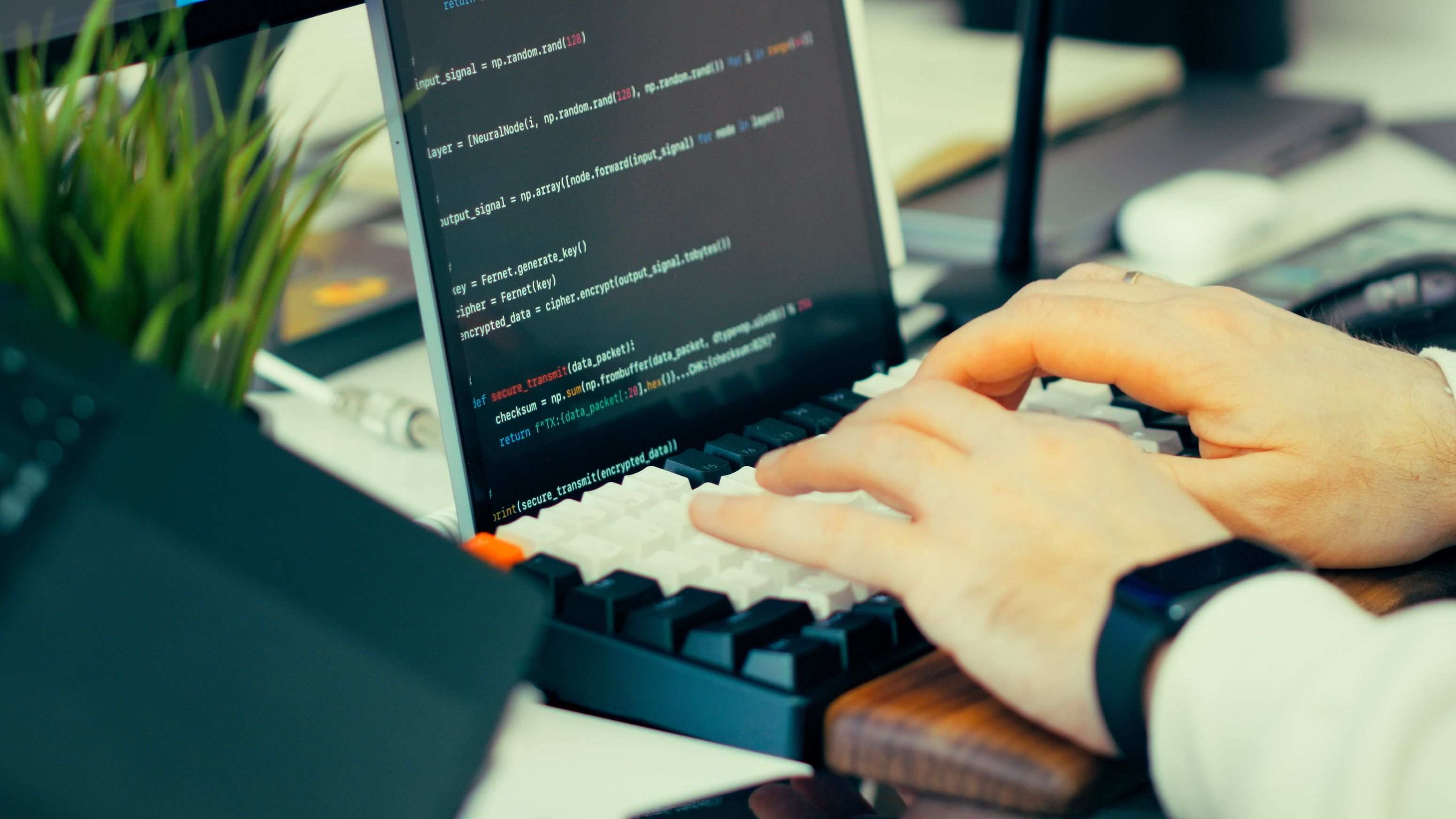 Hands typing on a laptop during a programming session, developer typing code on a keyboard